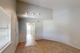 Located at 865 S Flannery Rd in Baton Rouge, Louisiana, this two-story home offers four bedrooms and three bathrooms spread across two well-proportioned floors. The main level provides the larger share of the living space, featuring a bright living room with soaring vaulted ceilings, track lighting, and a large window that draws in natural light. Carpet flooring runs throughout the living and bedroom areas, while wood-look flooring transitions into the kitchen and bathrooms. The kitchen is efficiently laid out with white cabinetry, light countertops, and white appliances including a refrigerator and dishwasher, complemented by a separate door that provides added functionality. The bathrooms are clean and straightforward, featuring vanities with lighted mirrors, tub-shower combinations, and wood-look flooring. The bedrooms are comfortably sized, each with carpet flooring and ceiling fans with light fixtures. The spacious primary bedroom includes direct access to a bathroom and benefits from a vaulted ceiling detail. Dedicated closet spaces with built-in shelving and hanging rods offer practical storage solutions. The upper floor houses additional bedrooms, accessible via a staircase, rounding out this functional and well-organized home.