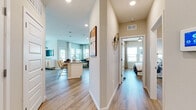 This single-floor residence is thoughtfully designed with a cohesive, contemporary aesthetic that flows seamlessly from room to room. Wood-look plank flooring runs throughout the entire unit, providing a warm and consistent foundation. Recessed lighting and large windows invite abundant natural light into every space.

The open-concept kitchen serves as a central hub, featuring white shaker-style cabinetry extending to the ceiling, a subway tile backsplash, stainless steel appliances, and a quartz-topped island with seating for casual dining. The adjacent living area offers a comfortable, neutral-toned environment with ample natural light from well-positioned windows.

A hallway connects the living spaces to the bedrooms. The primary bedroom is generously sized, accommodating a king bed with ease, and includes windows with outdoor views and a ceiling fan. The en-suite bathroom features an elongated dual-sink vanity with quartz countertops, white cabinetry, and a full soaking tub. A second well-proportioned bedroom is served by a similarly appointed bathroom with a single vanity and stylish finishes, maintaining a consistent design language throughout the residence.