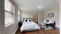 This single-floor unit offers a thoughtfully designed layout that balances comfort and functionality. The main living and sleeping area is generous in size, showcasing rich, dark hardwood flooring that adds warmth and character throughout. Large windows invite abundant natural light, and the neutral gray-toned walls create a clean, contemporary backdrop. The bedroom accommodates a full-size bed with ease and features a cozy seating nook, making it versatile as both a restful retreat and a casual lounge space. Classic crown molding and white trim detailing lend a refined architectural touch.

An arched doorway connects the sleeping area to the dining space, where light-toned tile flooring transitions smoothly from the hardwood. This charming architectural detail adds visual interest and a sense of flow between rooms. The compact dining area provides space for a table and chairs, ideal for everyday meals.

The kitchen is well-equipped with stainless steel appliances, including a gas range, built-in microwave, and full-size refrigerator. Rich, dark cabinetry paired with granite countertops and a decorative tile backsplash gives the kitchen a polished, modern aesthetic, with tile flooring completing the look.

The bathroom is clean and functional, featuring full-surround tile work in a neutral palette, a soaking tub, and a window for natural ventilation and light.