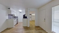 This well-appointed 1-bedroom, 1-bathroom unit offers a thoughtfully organized layout across a single floor, making efficient use of every square foot. Light-toned hardwood-style flooring runs consistently throughout the entire space, creating a cohesive and airy feel.

The open living area is bright and clean, featuring white walls, a ceiling fan with integrated lighting, and a window with blinds that invites natural light. The galley-style kitchen is well-equipped with white shaker cabinetry, white quartz countertops, a grey subway tile backsplash, and a full suite of stainless steel appliances including a refrigerator, dishwasher, and range. A partial peninsula separates the kitchen from the living area, adding functional counter space.

The bedroom is a comfortable, well-proportioned room with a ceiling fan, a window with blinds, and direct access to the bathroom. A built-in closet nook houses a stacked in-unit washer and dryer, a highly convenient feature. The bathroom is clean and modern, finished with white cabinetry, a quartz vanity countertop, a medicine cabinet mirror, and a full shower-tub combination. The overall aesthetic throughout is crisp, neutral, and move-in ready.