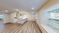 Located at Norwich Gate in East Norwich, NY, this thoughtfully updated single-floor residence offers a clean, modern aesthetic throughout. The open-concept living and dining area is anchored by warm-toned wood-look flooring, recessed lighting, and large windows dressed with blinds that allow generous natural light to fill the space. A peninsula-style kitchen seamlessly connects to the living area, showcasing crisp white shaker cabinetry, bright white quartz countertops, a white subway tile backsplash, and a full suite of stainless steel appliances including a refrigerator, electric range, over-the-range microwave, and dishwasher. Pendant lights above the peninsula add a stylish, contemporary touch. The bedrooms are finished with plush wall-to-wall carpeting and benefit from natural light via well-placed windows. The bathroom features a tub-shower combination accented with classic white subway tile and brushed nickel fixtures. A dedicated laundry area houses a full-size side-by-side washer and dryer with overhead shelving for added storage convenience. The space presents a cohesive, neutral palette throughout, creating a bright and inviting atmosphere that is both functional and move-in ready.