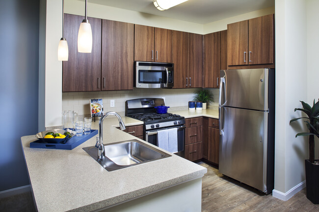 Cocina clásica de chocolate con gabinetes de nogal, placa para salpicaduras de azulejos, encimeras laminadas, pisos de superficie dura, y electrodomésticos de acero inoxidable - Avalon Framingham