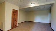 Located at 5303 Wilcox Rd in Charleston, West Virginia, this multi-story property spans three floors, providing a generous amount of usable space suited for a variety of purposes. The interior features a clean, neutral aesthetic with cream-colored walls and light-toned carpeting that lends a calm, understated atmosphere throughout.

From the available imagery, one of the lower-level rooms showcases a drop tile ceiling with flush-mounted lighting, providing even illumination across the open floor area. A solid wood six-panel door with warm, rich tones adds a touch of classic character to the space. Visible HVAC venting integrated into the ceiling supports efficient climate control. The room presents an open, flexible layout with no obstructions, making it adaptable for a range of uses.

The combination of durable flooring, practical ceiling infrastructure, and neutral wall tones creates a move-in-ready environment that can be customized with ease. With three full floors, the property offers significant vertical space and the potential for clearly defined functional zones across each level. Overall, the space presents a practical and well-maintained interior in a residential Charleston neighborhood.
