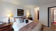This single-floor residence offers a thoughtfully arranged layout designed for comfortable everyday living. The living room provides a welcoming atmosphere, featuring plush carpeting, a wall-mounted decorative mirror that enhances the sense of space, and a wall unit for climate control. Natural light filters through vertical blinds, creating a bright and relaxed ambiance. Adjacent to the living area, the dining room is a cozy, intimate space accented by sage-green walls, decorative artwork, and a ceiling fan with a light fixture overhead. The galley-style kitchen is efficiently designed with rich dark wood cabinetry, white countertops, a double stainless steel sink, and black appliances, all complemented by light tile flooring and overhead fluorescent lighting that keeps the workspace well-lit. The primary bedroom is a serene retreat with soft carpeting, a roomy closet with bifold doors, and tasteful decorative accents. A secondary bedroom features vertical blinds, carpeted flooring, and a wall-mounted air conditioning unit, while a third bedroom, ideal for younger occupants, offers ample space with bunk bed accommodations and a bright window. The bathroom showcases a striking marble-patterned countertop, an undermount sink, and a well-lit vanity mirror, adding a refined touch to the space.