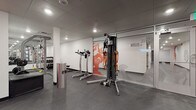 This fitness facility is thoughtfully laid out across a single floor, offering distinct zones tailored to different types of exercise. The main gym area features durable rubber flooring and is equipped with a multi-functional cable machine, TRX suspension trainer, adjustable benches, and a rack of dumbbells for strength training. A bold orange abstract mural decorates the white walls, adding an energetic visual element to the space. Glass partition walls branded with "Move + Burn" separate areas while maintaining an open, connected feel throughout.

The cardio zone is set against a striking red accent wall and houses treadmills, a rowing machine, and a stationary bike, each paired with wall-mounted flat-screen TVs for entertainment during workouts. Recessed and panel lighting keeps the area bright and functional.

A dedicated studio room provides a clean, open environment with smooth hardwood-style flooring ideal for yoga, dance, barre, or group fitness classes. Full-length mirrors span one wall, complemented by a ballet barre, wall-mounted TV, and stability balls for versatile training. Recessed ceiling lights and a cassette-style HVAC unit ensure a comfortable environment throughout. Together, these zones form a comprehensive and well-appointed fitness space.