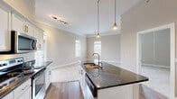 Located at 5541 Bowland Pl in Columbus, OH, this single-floor home offers a well-designed layout with a cohesive blend of modern finishes and functional living spaces. The kitchen serves as a central highlight, showcasing dark granite countertops, white shaker-style cabinetry, stainless steel appliances including a gas range, microwave, refrigerator, and dishwasher. A large center island with a undermount sink and stylish pendant lighting adds both elegance and practicality, while rich hardwood flooring flows throughout the kitchen and main corridor. Crown molding and neutral wall tones lend a refined touch to the open living area, which is bathed in natural light from multiple windows. The bedrooms feature plush wall-to-wall carpeting, vaulted ceilings in select rooms, and generous closet space, including a walk-in closet with built-in wire shelving systems for organized storage. The primary bathroom is appointed with large-format tile flooring, a glass-enclosed walk-in shower with a rainfall showerhead, a granite-topped vanity, and a well-lit mirror. A secondary bathroom provides a full tub-shower combination with wood-look flooring. Throughout the home, consistent use of white millwork, brushed nickel hardware, and neutral tones creates a clean, modern aesthetic.