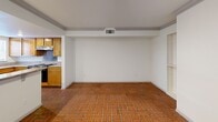Located in the heart of downtown Austin on East 4th Street, this two-bedroom, two-bathroom residence offers a functional and well-designed single-floor layout. The open living area makes an immediate impression with its striking terracotta brick-patterned tile flooring, crown molding, and recessed lighting, lending warmth and character to the space. Built-in shelving adds both storage and visual interest along one wall. The living area flows seamlessly into the kitchen, which features warm honey-toned wood cabinetry, granite-style laminate countertops, and a window that brings in natural light. Appliances include a range with overhead ventilation. The two bedrooms offer a comfortable retreat, with light wood laminate flooring, ceiling fans, and windows fitted with blinds for privacy. The spacious primary bedroom provides ample room for furnishings. Both bathrooms are finished with white tile flooring, vanities topped with granite-style counters, and white cabinetry. The full bathroom includes a tub-shower combination with tiled surround. Crown molding is a consistent detail throughout the residence, tying together the clean, neutral palette that characterizes the overall aesthetic.