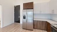Unit 114 at 1517 H Street presents a thoughtfully designed two-bedroom, two-bathroom residence spread across a single floor. The open-concept kitchen and living area serves as the heart of the unit, featuring tall ceilings that enhance the sense of space. The kitchen is outfitted with stainless steel appliances, including a side-by-side refrigerator with ice maker, a range, and a built-in microwave. Cabinetry combines white upper cabinets with warm wood-toned lower cabinets, complemented by a subway tile backsplash. Light-toned luxury vinyl plank flooring runs throughout the main living areas.

Both bedrooms are carpeted and benefit from large windows that frame views of a lush courtyard with tropical plantings, filling the rooms with natural light. The primary bedroom includes access to a dedicated walk-in closet with built-in shelving. Each bathroom features a tub-shower combination with marble-style surround panels, a wood-toned vanity with white countertop, and LVP flooring. Three closets provide ample storage throughout the unit. The overall aesthetic is clean and contemporary, with a neutral white palette and modern finishes throughout.