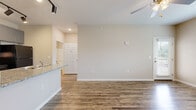 This single-floor residence offers a clean, contemporary design with a neutral color palette and thoughtful finishes throughout. The open living area is anchored by durable wood-look flooring that runs throughout the main living spaces, complemented by a ceiling fan with integrated lighting and windows dressed with horizontal blinds that allow ample natural light to fill the room. A private entrance door leads directly into the living space, reinforcing a sense of accessibility and ease.

The kitchen is a functional highlight of the home, featuring granite-look countertops, grey shaker-style cabinetry with brushed nickel hardware, and a full suite of black appliances including a refrigerator, electric range with over-the-range microwave, and dishwasher. A peninsula counter with a double-basin stainless steel sink provides additional workspace and a natural transition into the living area.

The bedrooms offer plush wall-to-wall carpeting and windows that invite natural light, creating warm, restful spaces. The bathroom continues the home's cohesive aesthetic with a distinctive blue vanity topped with granite-look counters, a large mirror, and wood-look flooring, providing a fresh and modern feel. Throughout the home, white six-panel doors, clean baseboards, and recessed lighting add to the polished, move-in-ready presentation.