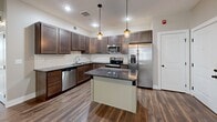 Located at 221 Trowbridge St in Grand Rapids, MI, this 2-bedroom, 2-bathroom unit offers a well-designed single-floor layout that makes efficient use of its space. The open-concept living, dining, and kitchen area serves as the heart of the home, featuring rich hardwood-style flooring, warm two-tone wall colors, and natural light from multiple windows with blinds. The kitchen is a standout, outfitted with dark granite countertops, rich espresso-toned cabinetry, a white subway tile backsplash, a center island with pendant lighting, and a full suite of stainless steel appliances including a refrigerator with ice maker, electric range, microwave, and dishwasher. Both bedrooms are carpeted and bathed in natural light, offering a comfortable and quiet retreat with dedicated closets. The two bathrooms feature earthy stone-look tile flooring — one with a walk-in shower and the other with a tub-shower combo. Additional highlights include an in-unit laundry area and recessed lighting throughout. The layout flows logically, making the space feel cohesive and functional throughout.