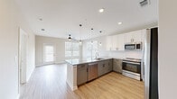 Located at 110 Addison Dr in Athens, Georgia, this single-floor residence offers a thoughtfully designed open-concept layout with contemporary finishes throughout. The kitchen serves as the heart of the home, showcasing two-tone cabinetry with white upper cabinets and sage-gray lower cabinets, granite countertops, a classic subway tile backsplash, and stainless steel appliances including a range, microwave, and dishwasher. A central island with an integrated sink adds both functionality and visual appeal, while pendant lighting and recessed fixtures illuminate the space. Light wood-look flooring flows seamlessly through the kitchen and into the adjacent living area, which benefits from multiple windows that invite generous natural light. A ceiling fan adds comfort to the open living space, which also provides access to the outdoors. The bathroom features consistent granite countertops, gray shaker-style cabinetry, a glass-enclosed walk-in shower with tile surround, and matching wood-look flooring. Bedrooms are finished with plush carpeting, neutral tones, and windows that bring in natural light. The primary bedroom includes a spacious walk-in closet with wire shelving for organized storage. Throughout the home, a cohesive neutral palette and modern hardware create a clean, inviting atmosphere.