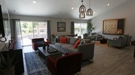 This single-floor residence offers a thoughtfully designed layout that balances comfort and functionality throughout. The living room serves as the heart of the home, featuring soft carpeting, cool gray walls, and a large sliding glass door that opens to a private balcony, flooding the space with natural light and providing pleasant outdoor views. A wall-mounted television and a round decorative mirror add character to the room.

The kitchen is a standout feature, boasting rich dark cabinetry, white countertops, a peninsula with bar seating, and a full suite of stainless steel appliances, including a gas range and over-the-range microwave. A tray ceiling with recessed lighting adds architectural interest overhead. Adjacent to the kitchen, the dining area features hardwood-style flooring and a ceiling fan.

The primary bedroom is a serene retreat with plush carpet, mirrored sliding closet doors, and a natural window. Two additional bedrooms provide comfortable accommodations, one of which features carpet and a mirrored closet. The bathrooms are well-finished, with one offering a tub-shower combo and hardwood-style flooring, and another featuring a dark wood vanity with a wide mirror and modern light fixture. The residence presents a warm, livable atmosphere throughout its well-connected rooms.