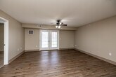 Located at 610 E Scenic Valley Ave in Indianola, Iowa, this single-floor, 2-bedroom, 2-bathroom home offers a well-organized layout designed for comfortable everyday living. The combined kitchen and living room serves as the heart of the home, with warm hardwood-style flooring that reflects natural light streaming through double French doors. A ceiling fan overhead adds both style and function to the spacious living area. The kitchen is equipped with rich cherry wood cabinetry, granite-style countertops, and white appliances including a range, dishwasher, and hood vent, all set atop matching hardwood-style flooring. Both bedrooms are generously sized, featuring plush wall-to-wall carpeting, ceiling fans with light fixtures, and windows that invite natural light. The primary bedroom offers a comfortable footprint with ample room for furnishings. Each bathroom features cherry wood vanities with white countertops and hardwood-style flooring, while one bathroom includes a walk-in roll-in shower with grab bars and a handheld showerhead, offering accessibility-friendly design. Three closets provide excellent storage throughout. A dedicated laundry room adds everyday convenience. Neutral warm-beige tones and clean white trim carry throughout, creating a cohesive and inviting atmosphere.