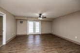Located at 610 E Scenic Valley Ave in Indianola, Iowa, this single-floor, 2-bedroom, 2-bathroom home offers a well-organized layout designed for comfortable everyday living. The combined kitchen and living room serves as the heart of the home, with warm hardwood-style flooring that reflects natural light streaming through double French doors. A ceiling fan overhead adds both style and function to the spacious living area. The kitchen is equipped with rich cherry wood cabinetry, granite-style countertops, and white appliances including a range, dishwasher, and hood vent, all set atop matching hardwood-style flooring. Both bedrooms are generously sized, featuring plush wall-to-wall carpeting, ceiling fans with light fixtures, and windows that invite natural light. The primary bedroom offers a comfortable footprint with ample room for furnishings. Each bathroom features cherry wood vanities with white countertops and hardwood-style flooring, while one bathroom includes a walk-in roll-in shower with grab bars and a handheld showerhead, offering accessibility-friendly design. Three closets provide excellent storage throughout. A dedicated laundry room adds everyday convenience. Neutral warm-beige tones and clean white trim carry throughout, creating a cohesive and inviting atmosphere.