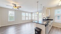 Located at 4101 Runner Lp in Chester, VA, this well-appointed 2-bedroom, 2-bathroom residence offers a thoughtfully designed single-floor layout with modern finishes throughout. The open-concept kitchen and living area serves as the heart of the home, featuring a peninsula with dark granite countertops, pendant lighting, and a full suite of stainless steel appliances including a refrigerator, range, and microwave. White shaker-style cabinetry with black hardware provides ample storage, while light hardwood-style flooring and large windows with blinds fill the space with natural light. A ceiling fan anchors the living area, which benefits from views of the surrounding neighborhood. The primary bedroom is a comfortable retreat with plush carpeting, a ceiling fan, and natural light streaming through large windows. A dedicated closet with double doors adds practical storage. The primary bathroom features a dual-sink vanity with dark granite countertops and a tiled tub-shower combination. The second bedroom also offers carpeted floors, a ceiling fan, and generous natural light. The second bathroom includes a clean walk-in shower with white tile surround and a glass door. The overall aesthetic is bright, neutral, and contemporary throughout.