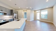 Located at 2520 N Central Expy in Richardson, TX, this well-appointed one-bedroom, one-bathroom unit offers a thoughtfully designed single-floor layout. The open-concept kitchen and living area serves as the heart of the space, showcasing two-tone gray shaker cabinetry with matte black hardware, a marble-style tile backsplash, crisp white countertops, and a full suite of stainless steel appliances including a range, built-in microwave, and French door refrigerator. A large center island with an undermount sink adds both workspace and casual seating potential. Light wood-look flooring runs throughout the main living areas, complementing the neutral, warm-toned walls. The living area features a glass door with transom window and an adjacent window fitted with blinds, allowing natural light to fill the space while offering outdoor views. The bedroom is comfortably sized, finished with plush carpet, a ceiling fan, and a window overlooking the exterior. A dedicated closet provides practical storage. The bathroom features large-format neutral tile on both the walls and floor, a soaking tub with an overhead shower, a curved curtain rod, and a built-in niche — delivering a clean and polished aesthetic throughout.