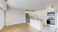 Located at 851 Richmond Rd in Ottawa's vibrant west end, this modern one-bedroom, one-bathroom unit offers a thoughtfully designed layout across a single floor. The open-concept living and kitchen area serves as the heart of the space, featuring light hardwood flooring that flows seamlessly throughout. The kitchen is outfitted with crisp white cabinetry extending to the ceiling for generous storage, a central island with a dark quartz countertop, a full suite of stainless steel appliances including a refrigerator, stove, microwave, and dishwasher, and a subway tile backsplash. Recessed pot lighting illuminates the kitchen, while a sliding glass door with vertical blinds fills the living area with natural light and provides access to outdoor views of Richmond Road. The bedroom is a well-proportioned, quiet retreat also benefiting from a large sliding window with vertical blinds. The bathroom features a white vanity with a dark countertop, a framed mirror, tiled flooring, and a full bathtub with a tiled surround. A clean hallway with flush ceiling lighting and a built-in ventilation system connects all rooms. The overall aesthetic is contemporary and neutral, with a bright, airy ambiance throughout.