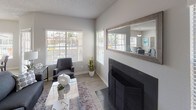 This single-floor residence offers a comfortable and functional layout with a cohesive neutral color palette throughout. The living room is a standout space, featuring a tiled fireplace with a classic black surround, wood-look flooring, a textured ceiling, and multiple windows fitted with horizontal blinds that invite abundant natural light while maintaining privacy. A ceiling fan adds practicality to the space. The kitchen is equipped with white cabinetry, stainless steel appliances including a range, over-the-range microwave, and refrigerator, complemented by a subway tile backsplash and wood-look flooring. Adjacent to the kitchen, the dining area accommodates a glass-top table and benefits from a large window with outdoor views. The primary bedroom is generously sized with plush carpeting, a textured ceiling, a walk-in closet, and a window overlooking the surroundings. Its en-suite bathroom features a single-sink vanity, wood-look tile flooring, and a tub-shower combination. The second bedroom also features carpeting, a window with natural light, and ample storage. A second full bathroom includes a tub-shower combination with clean white tile surround and chrome fixtures, completing this well-designed residence.
