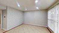 Located at 7637 Harwin Dr in Houston, TX, this single-floor, one-bedroom, one-bathroom unit offers a functional and well-appointed layout. Light-toned ceramic tile flooring runs throughout the entire space, creating a cohesive and easy-to-maintain interior. A striking white-painted brick accent wall serves as a defining architectural feature, adding texture and character to both the living and bedroom areas.

The dining area near the entrance is highlighted by an elegant chandelier and benefits from natural light, while a built-in shelving nook with a stone tile accent provides a decorative focal point. The kitchen is efficiently designed with white cabinetry, granite-style countertops, a stone tile backsplash, and black appliances including a range and refrigerator. Recessed lighting and an overhead ventilation hood complete the functional cooking space.

The spacious primary bedroom features a ceiling fan with integrated lighting, a window with natural light, and direct access to both a dedicated closet and the full bathroom. The bathroom includes a clean, white-tiled tub and shower combination. A separate laundry room with washer and dryer hookups adds everyday convenience. Neutral gray walls throughout lend a modern, move-in ready aesthetic to this well-organized Houston residence.
