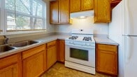 Located at 7015C Christian Loop in Fort Meade, Maryland, this two-floor home offers a practical and comfortable layout designed for everyday living. The main level features a well-appointed kitchen equipped with warm oak cabinetry, ample counter space, a gas range, and a sink positioned beneath a window that brings in natural light. A half bath on this level includes a pedestal sink, medicine cabinet mirror, and tile-style flooring, providing added convenience for residents and guests. A staircase connects the two floors, giving the home a sense of vertical space and openness. The upper level hosts the carpeted bedrooms, each finished with neutral tones and bright walls that create a clean, welcoming atmosphere. One bedroom benefits from dual windows and a ceiling fan, ensuring comfort and airflow, while another features a wide window overlooking greenery outside. Bedroom closets are generously sized with built-in rod systems for organized storage. The full bathroom on the upper level is outfitted with a soaking tub and shower surround in crisp white, complemented by a mirrored medicine cabinet. Throughout the home, soft carpeting in the living areas and bedrooms adds warmth, while tile flooring in the wet areas provides durability. The overall ambiance is bright, neutral, and move-in ready.