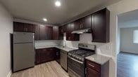 Located at 6605-25 Clayton Ave in St. Louis, MO, this thoughtfully updated single-floor unit offers a clean, modern aesthetic with quality finishes throughout. The open-concept layout connects the kitchen and living area seamlessly, with durable wood-look flooring extending across the main living spaces and natural light filtering in through windowed rooms.

The kitchen is a standout feature, outfitted with rich dark espresso cabinetry, granite countertops, a classic subway tile backsplash, and a full suite of stainless steel appliances including a gas range, dishwasher, and refrigerator. Recessed lighting enhances the functional workspace.

The living area is bright and open, flowing naturally from the kitchen and offering ample space for a variety of furniture arrangements. The entry area provides a welcoming transition into the main living space.

The unit includes two bathrooms, each finished with marble-look tile. One bathroom features a soaking tub with a full tiled surround, while the second offers a glass-enclosed walk-in shower, a dark vanity with granite countertop, and large-format floor tile. The bedrooms are generously proportioned with neutral walls and wood-look flooring, providing a versatile canvas for personalization.