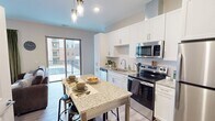 This contemporary 620 square foot apartment offers a thoughtfully designed living space. The open-concept layout combines the kitchen and living area, creating a sense of spaciousness. The kitchen boasts white cabinetry, stainless steel appliances, and a granite countertop island that doubles as a dining space. The living room features a comfortable sectional sofa, modern coffee table, and an electric fireplace, all anchored by a geometric area rug.

The bedroom, measuring 120 square feet, is well-appointed with a queen-sized bed, wooden nightstands, and a large window allowing ample natural light. A sizable closet provides generous storage space with wire shelving systems.

The bathroom showcases a marble-look shower enclosure, modern vanity, and sleek fixtures. Throughout the apartment, wood-look flooring adds warmth and continuity.

A private balcony offers outdoor space and city views, enhancing the overall living experience. The apartment's design emphasizes functionality and style, making efficient use of its compact footprint while providing all the amenities of a larger home.