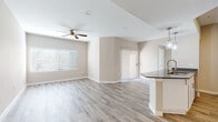 This single-floor home offers a thoughtfully designed open-concept layout that seamlessly connects the living, dining, and kitchen areas. The main living space is finished with light wood-look flooring and neutral beige walls, creating a bright and welcoming ambiance. A ceiling fan overhead and a large window with blinds allow for natural light and comfortable airflow throughout the space.

The kitchen is equipped with stainless steel appliances, including a range, microwave, and refrigerator, complemented by crisp white cabinetry and dark countertops. A kitchen island with pendant lighting serves as both a functional workspace and a visual centerpiece, with a sleek faucet and sink integrated into the design.

The bedrooms feature plush carpeting and ceiling fans, with generous windows dressed in blinds that invite natural light. Each room offers a calm, neutral palette well-suited for a variety of uses.

Two bathrooms provide distinct functionality. One includes a soaking tub with a marble-look tile surround and wood-look tile flooring, while the other features a walk-in glass-door shower with matching marble-look tile. Both bathrooms are finished with brushed nickel fixtures and dark countertops, lending a cohesive, modern aesthetic throughout the home.