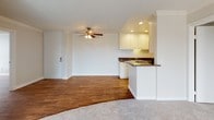 Located at 4351 Boardwalk Dr in Huntington Beach, CA, this single-level residence offers a well-designed layout with consistent finishes throughout. The open-concept living and dining area is anchored by warm wood-look flooring, crown molding, a textured ceiling, and a ceiling fan. A sliding glass door leads to a private balcony overlooking lush greenery, filling the space with natural light. A striking stacked-stone accent wall frames the fireplace, adding a distinctive architectural detail to the main living area.

The galley-style kitchen is outfitted with white cabinetry extending to the ceiling, dark granite countertops, a double stainless steel sink, and black appliances, including an electric range and over-the-range microwave. A peninsula with a breakfast bar connects the kitchen to the living area. A separate wet bar area with matching white cabinetry, granite counters, and a sink provides additional functionality.

The bedrooms feature plush carpet and generous closet space. One bedroom includes a dedicated vanity nook with granite counters and lighted mirror. The bathrooms are finished with white cabinetry, granite countertops, wood-look flooring, and tub/shower combinations, maintaining a cohesive aesthetic throughout the residence.
