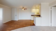 Located at 4351 Boardwalk Dr in Huntington Beach, CA, this single-level residence offers a well-designed layout with consistent finishes throughout. The open-concept living and dining area is anchored by warm wood-look flooring, crown molding, a textured ceiling, and a ceiling fan. A sliding glass door leads to a private balcony overlooking lush greenery, filling the space with natural light. A striking stacked-stone accent wall frames the fireplace, adding a distinctive architectural detail to the main living area.

The galley-style kitchen is outfitted with white cabinetry extending to the ceiling, dark granite countertops, a double stainless steel sink, and black appliances, including an electric range and over-the-range microwave. A peninsula with a breakfast bar connects the kitchen to the living area. A separate wet bar area with matching white cabinetry, granite counters, and a sink provides additional functionality.

The bedrooms feature plush carpet and generous closet space. One bedroom includes a dedicated vanity nook with granite counters and lighted mirror. The bathrooms are finished with white cabinetry, granite countertops, wood-look flooring, and tub/shower combinations, maintaining a cohesive aesthetic throughout the residence.