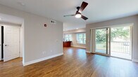 This single-floor residence offers a thoughtfully designed layout with a cohesive, neutral aesthetic throughout. The open living area is anchored by warm hardwood-style flooring and a ceiling fan with integrated lighting. A sliding glass door leads directly to a private balcony overlooking lush greenery, filling the space with abundant natural light. The living area flows seamlessly toward a dining nook and kitchen, where rich warm-toned cabinetry pairs with white quartz countertops, a classic subway tile backsplash, and a full suite of stainless steel appliances, including a gas range, built-in microwave, and French door refrigerator. A pendant light and a large window brighten the kitchen further. The bedrooms feature plush wall-to-wall carpeting, ceiling fans, and ample natural light from well-placed windows. Walk-in closet access is available from the primary bedroom, which connects to a private bathroom finished with a white quartz vanity, an undermount sink, and warm wood cabinetry. A dedicated in-unit laundry closet and an additional full bathroom with a tub complete this well-rounded residence.