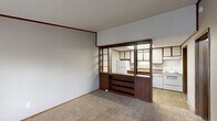 This single-floor, 2-bedroom, 1-bathroom residence in Augusta, Georgia offers a practical and functional layout. The living area features neutral carpet flooring, crown molding, and a textured ceiling, while a standout wood-framed, open-shelving room divider with glass panels separates the space from the kitchen, creating a semi-open feel without sacrificing definition between rooms. The kitchen is equipped with white appliances, including a refrigerator and range, under-cabinet lighting, ample cabinetry, and laminate countertops, with hard-surface flooring for easy maintenance. The entry area features a large window with blinds that allows natural light to fill the space, along with a built-in unit beneath the window and a transition from carpet to hardwood-style flooring at the front door. The spacious primary bedroom is carpeted and includes a ceiling fan with light fixture and a window overlooking the outdoors. The second bedroom provides additional flexibility, featuring carpet flooring, crown molding, a closet with shelving, and direct hallway access. The full bathroom includes a tub/shower combination and hard-surface flooring. A dedicated utility room completes the layout, adding valuable storage and functional space to this efficiently designed residence.