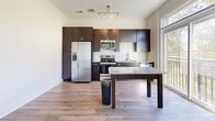 Located at 900 E Brooklyn Village Ave in Charlotte, NC, this one-bedroom, one-bathroom residence offers a well-designed single-level layout with contemporary finishes throughout. Wood-style plank flooring runs continuously across all rooms, creating a cohesive and clean aesthetic.

The kitchen is a standout feature, equipped with full stainless steel appliances including a side-by-side refrigerator, electric range, built-in microwave, and dishwasher. Rich dark espresso cabinetry extends to the ceiling for ample storage, while granite countertops and a textured tile backsplash add refined detail. A kitchen island with a matching granite surface provides additional prep space and casual dining potential. A track lighting fixture illuminates the area, and a large window invites natural light.

The bedroom is a comfortable, neutral space with soft grey walls, crisp white trim, and access to a closet with louvered doors, offering practical storage.

The bathroom is finished with a dark espresso vanity topped with granite, a tiled tub-surround shower, and coordinating wood-style flooring, maintaining the consistent design language of the home. Clean white walls and brushed nickel fixtures complete the polished look.