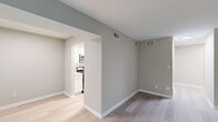 This single-floor space presents a cohesive, neutral palette with modern updates throughout. The open living area is finished with light wood-look flooring and warm gray walls, creating a bright and versatile environment. A sliding glass door opens directly onto a private deck overlooking mature trees, bringing natural light and greenery into the space.

The kitchen is thoughtfully designed with white shaker-style cabinetry, quartz countertops featuring subtle speckled detailing, a stainless steel sink, and stainless steel appliances including a refrigerator, dishwasher, microwave, and range. Ample upper and lower cabinetry provides generous storage, and the layout flows efficiently for everyday use.

The bedrooms feature plush carpeting and closets with louvered sliding doors, offering practical storage. Natural light filters in through windows with horizontal blinds. Additional rooms with wood-look flooring provide flexible living or office space.

The bathroom includes a full tub-shower combination with white subway tile surround and chrome fixtures, maintaining the clean, neutral aesthetic found throughout the unit. HVAC vents are present in multiple rooms, ensuring consistent climate control. The overall ambiance is fresh, functional, and move-in ready.