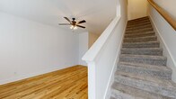 Located at 630 Huntco Drive in Clarksville, Tennessee, this two-story home offers 2 bedrooms and 3 bathrooms across two well-proportioned floors. The main level provides a bright, open living area with light hardwood-style flooring, a ceiling fan with light fixture, and natural light streaming through front-facing windows and a paneled entry door. The kitchen is a standout feature, showcasing gray shaker-style cabinetry, granite countertops, a peninsula with pendant lighting, stainless steel appliances including a range, microwave, dishwasher, and refrigerator, and a matte black sink fixture — all flowing seamlessly into the living space. A half or full bathroom on the main level features hardwood-style flooring, gray vanity cabinetry with matte black hardware, and clean white walls. Carpeted stairs with a white painted banister lead to the upper level, where both bedrooms are found, each with plush neutral carpet and crisp white walls. The spacious primary bedroom includes its own bathroom with a soaking tub, vanity, and classic white fixtures. An additional full bathroom serves the second bedroom. Throughout, the home maintains a clean, modern aesthetic with consistent white trim, matte black accents, and a bright, neutral palette.