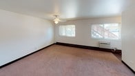 This two-story residence at 1954 Memorial Dr in Calumet City, Illinois, offers a practical and well-organized layout across two floors. The main level features an open living area with plush carpeting, neutral white walls, and a staircase leading to the upper floor. The kitchen is positioned just off the living space and is equipped with rich, dark wood cabinetry, light countertops, a double-basin sink, and a white gas range with an overhead ventilation hood. Dark hardwood-style flooring in the kitchen adds contrast to the cabinetry. A half bathroom on the main level includes a wood-framed vanity mirror, single-sink vanity with cabinet storage, and hardwood-style flooring. The upper floor hosts multiple bedrooms, each finished with wall-to-wall carpeting and sliding windows that allow natural light and views of the surrounding exterior. One bedroom features a ceiling fan light fixture, while another includes a closet with sliding doors and built-in shelving. A full bathroom upstairs provides a bathtub and shower combination, a single-sink vanity, a wood-framed medicine cabinet mirror, and bright overhead lighting. Throughout the home, dark baseboards provide a clean finish against the light-colored walls.