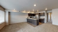 Located at 3965 S 300 E in Salt Lake City, Utah, this single-floor unit offers a thoughtfully designed open-concept layout that seamlessly connects the kitchen and living areas. The kitchen serves as a central focal point, showcasing rich dark espresso cabinetry, light granite countertops, and a full suite of stainless steel appliances including a range, microwave, and refrigerator. A peninsula with matching cabinetry and granite provides additional workspace and casual seating, while wood-style flooring grounds the kitchen zone before transitioning to plush carpet throughout the living and bedroom areas.

The spacious living area benefits from multiple windows fitted with blinds, allowing for ample natural light. A sliding glass door in one room provides direct outdoor access. The bedrooms are carpeted and well-proportioned, with one featuring a window with a built-in storage bench.

Two bathrooms reflect the same refined finishes found in the kitchen. The primary bathroom includes a double-sink vanity with granite counters, dark cabinetry, a walk-in glass shower, and wood-style flooring. The secondary bathroom features a single-sink vanity with matching granite and cabinetry. Recessed lighting and neutral tones throughout create a clean, modern ambiance.