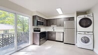 Located in Blakely, PA, this well-designed two-story home offers 2 bedrooms and 2 bathrooms spread evenly across two floors. The main level features a bright, open living room finished with large-format tile flooring and recessed lighting, creating a clean and airy atmosphere. Natural light filters in through windows framing views of the surrounding greenery. The kitchen is a standout, outfitted with dark shaker-style cabinetry, white subway tile backsplash, stainless steel appliances including a range, microwave, dishwasher, and refrigerator, and a sliding glass door that opens to an outdoor deck. A stacked washer and dryer unit is also conveniently housed in the kitchen area. One full bathroom on this level features a white vanity with black matte fixtures and a rounded mirror, adding a contemporary touch. Upstairs, the two bedrooms offer light hardwood-style flooring, built-in closets, and windows overlooking the wooded surroundings. The primary bedroom is a comfortable size with ample closet space. The second bathroom continues the modern aesthetic with neutral tile flooring and a sleek vanity. Throughout the home, crisp white walls, black hardware accents, and consistent finishes create a cohesive, updated look.
