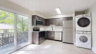 Located in Blakely, PA, this well-designed two-story home offers 2 bedrooms and 2 bathrooms spread evenly across two floors. The main level features a bright, open living room finished with large-format tile flooring and recessed lighting, creating a clean and airy atmosphere. Natural light filters in through windows framing views of the surrounding greenery. The kitchen is a standout, outfitted with dark shaker-style cabinetry, white subway tile backsplash, stainless steel appliances including a range, microwave, dishwasher, and refrigerator, and a sliding glass door that opens to an outdoor deck. A stacked washer and dryer unit is also conveniently housed in the kitchen area. One full bathroom on this level features a white vanity with black matte fixtures and a rounded mirror, adding a contemporary touch. Upstairs, the two bedrooms offer light hardwood-style flooring, built-in closets, and windows overlooking the wooded surroundings. The primary bedroom is a comfortable size with ample closet space. The second bathroom continues the modern aesthetic with neutral tile flooring and a sleek vanity. Throughout the home, crisp white walls, black hardware accents, and consistent finishes create a cohesive, updated look.