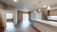 Located at 4401 W Oak St in Rogers, Arkansas, this single-floor 2-bedroom, 2-bathroom home offers a thoughtfully designed layout with modern finishes throughout. The open-concept kitchen is a standout feature, showcasing rich dark-stained cabinetry, granite countertops, stainless steel appliances including a refrigerator, microwave, and range, and a large central island with a undermount sink illuminated by stylish pendant lighting. The kitchen flows seamlessly into the living room, which features durable hardwood-style flooring, a ceiling fan, and sliding glass door access that fills the space with natural light. Each bedroom is generously sized, fitted with ceiling fans and hardwood-style flooring, and benefits from natural light through well-placed windows. The spacious primary bedroom includes direct access to its own bathroom and a large walk-in closet with wire shelving systems offering ample storage. The second bedroom is served by a full bathroom with a tub-shower combination and a dark-toned vanity. A second walk-in closet provides additional storage. Neutral warm-toned walls complement the light flooring throughout, creating a clean, cohesive aesthetic across the entire home.