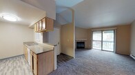 This single-floor apartment at 24028 SE 110th Pl, Unit N301 in Kent, Washington offers a well-organized layout with a range of functional and comfortable features throughout. The open living area is defined by striking vaulted ceilings and a ceiling fan, creating an airy and spacious atmosphere. A fireplace with a tile surround serves as a focal point in the living room, which also benefits from natural light and direct access to a balcony through sliding glass doors. The galley-style kitchen is efficiently designed with light wood cabinetry, granite-style countertops, a double sink, and white appliances including a range and refrigerator, all set on light hardwood-style flooring. The bedrooms are carpeted and well-proportioned; one features a built-in window seat, while another includes sliding wood-panel closet doors offering ample storage. The bathroom is clean and functional, featuring a tub-shower combination, a single vanity with stone-style countertop, and light wood-style flooring. Baseboard heating is present throughout the unit. Neutral warm tones on the walls, plush carpeting in living and sleeping areas, and consistent finishes give the entire space a cohesive and inviting character.