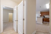 This single-floor residence offers a thoughtfully designed layout with a cohesive neutral palette of warm beige tones and white trim throughout. The kitchen serves as a functional centerpiece, featuring rich medium-toned wood cabinetry extending to the ceiling with crown molding accents, granite countertops, a central island with pendant lighting above, and a full suite of black appliances including a refrigerator, range, microwave, and dishwasher. Light ceramic tile flooring runs through the kitchen and connects seamlessly to the entry hallway.

The living area impresses with vaulted ceilings and a ceiling fan, complemented by double doors that invite natural light and outdoor views. Soft wall-to-wall carpeting extends through the living spaces and bedrooms, adding warmth underfoot. Bedrooms are generously proportioned, with at least one featuring a walk-in closet with built-in shelving and a window with outdoor views.

Both bathrooms are finished with matching granite-topped wood vanities, tile flooring, large mirrors, and ample storage. The full bath includes a tub and shower combination. A hallway with louvered closet doors provides additional storage. Crown molding and white panel doors are consistent throughout, contributing to a polished, unified aesthetic.