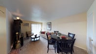 Located at 700 Saint Marys Ave in Frankfort, Indiana, this single-floor residence offers a comfortable and functional layout designed for everyday living. The open-concept living and dining area forms the heart of the home, creating a seamless flow between spaces. The living area is carpeted and features a wall-mounted air conditioning unit, vertical blinds, and a sliding glass door that allows natural light to brighten the room. The dining area sits adjacent to the living space and comfortably accommodates a round dining table with seating for four, making it well-suited for both daily meals and casual entertaining. Warm, neutral-toned walls complement the light carpeting throughout, contributing to a welcoming and cohesive atmosphere. The textured ceiling adds a traditional touch to the interior. The sliding glass door provides access to an outdoor area while enhancing the sense of openness within the main living space. Overall, the layout is practical and efficiently organized, offering residents a straightforward and livable environment in a residential neighborhood in Frankfort, Indiana.