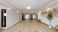 Located at 418 N Norton Ave in the heart of Los Angeles, this building entrance lobby offers a well-appointed and functional space that sets a welcoming tone for residents and visitors alike. The lobby is finished with distinctive patterned ceramic tile flooring in warm earth tones, lending a stylish and cohesive aesthetic throughout the space.

Natural light pours in through large glass double-entry doors framed in sleek black, offering views of the tree-lined streetscape outside. The bright white walls and recessed ceiling lighting further enhance the open, airy ambiance of the interior.

Two stainless steel elevators are prominently positioned at the rear of the lobby, framed by a decorative tile accent wall that adds visual interest and architectural character. Flanking the elevators are dark-finished stairwell doors, providing clear and accessible circulation options.

Along one wall, a full bank of individual mailboxes serves residents' postal needs, complemented by a modern smart parcel locker system for secure package deliveries. A large, layered macramé wall installation serves as a striking decorative focal point, adding a bohemian, artisanal touch to the space.

Thoughtful finishing details include potted olive trees, a wooden bench for seating, and additional side tables, creating a comfortable and inviting atmosphere in this well-designed residential lobby.