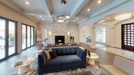 This single-story clubhouse and leasing center for Radius at Cheshire Bridge is a beautifully renovated communal space designed with sophistication and comfort in mind. The interior showcases a refined aesthetic defined by coffered ceilings with decorative crown molding, herringbone-patterned hardwood flooring, and arched architectural details that lend a classical elegance to the layout.

The main lounge area serves as the centerpiece of the space, anchored by a floor-to-ceiling stone fireplace and a large wall-mounted television framed in rich wood paneling. Curated furnishings — including a deep navy velvet sofa, mixed accent chairs, and artful area rugs — create an inviting, upscale atmosphere. A large potted fiddle-leaf fig tree adds a natural focal point to the room.

An expansive wall of black-framed glass doors and floor-to-ceiling windows floods the interior with natural light and provides direct views of the outdoor pool and patio area, seamlessly connecting the indoor and outdoor spaces. The pool terrace is visible with lounge seating, tall planters, and a pergola structure beyond.

Recessed lighting and pendant fixtures contribute to a warm, layered lighting scheme throughout. Overall, the space reflects a high standard of design that aligns with its newly renovated, amenity-rich residential community positioning.