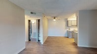 This single-floor unit offers a clean, modern aesthetic with a practical and functional layout throughout. The open living and dining area is finished with wood-look plank flooring, neutral gray walls, and a textured ceiling, creating a bright and welcoming atmosphere. A ceiling fan provides comfort and airflow to the main living space, which also features a generously sized mirrored closet with built-in shelving, offering ample storage.

The galley-style kitchen is well-equipped with gray shaker cabinets, light quartz-style countertops, a stainless steel sink, and a full suite of appliances including a black electric range, over-the-range microwave, and refrigerator. The kitchen connects seamlessly to the living area, making the space feel cohesive and accessible.

The bedroom is a comfortable, enclosed room finished with plush dark carpeting and neutral gray walls, providing a quiet and restful retreat. The full bathroom features a tub-shower combination with a curtain rod, grab bar for added safety, a toilet, and a vanity with a stone-look countertop — all finished in clean, neutral tones.

Wood-look flooring flows consistently through the main living areas, tying the space together with a cohesive, contemporary feel throughout.