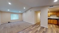 This single-story home is thoughtfully designed with a cohesive neutral color palette and a mix of flooring materials that create visual interest throughout. The main living area is a standout space, featuring dramatic vaulted ceilings with recessed lighting that enhance the sense of openness. Wood-look plank flooring transitions seamlessly into plush carpeting, defining separate functional zones within the room. A large window allows natural light to fill the space, contributing to its bright and airy atmosphere.

The kitchen is well-appointed with warm honey-toned wood cabinetry, bold dark granite countertops, a stainless steel sink, and stainless steel appliances including a gas range, microwave, and dishwasher. A hallway with wood-look flooring and recessed lighting connects the main living areas to the additional rooms, which feature carpeted floors and ample closet space. One bedroom includes a ceiling fan and a window for natural ventilation and light.

The bathroom is finished with tile flooring, a dark granite-topped vanity with a large mirror, stylish wall-mounted lighting, and a full tub-shower combination, completing this well-appointed home.