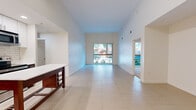 Located at 899 N Orange Ave in Orlando's vibrant 32803 corridor, this 2-bedroom, 2-bathroom residence offers a thoughtfully designed single-floor layout with a clean, contemporary aesthetic. The open-concept living area immediately impresses with soaring ceilings and large windows that flood the space with natural light while framing views of the surrounding greenery. Large-format light tile flooring extends seamlessly across the living room and kitchen, enhancing the sense of openness.

The kitchen is well-appointed with white upper cabinetry, rich dark wood lower cabinets, a subway tile backsplash, stainless steel appliances including a refrigerator, range, and microwave, and a white countertop island unit that provides additional prep and storage space.

Both bedrooms feature plush carpeting, ceiling fans, and generous windows that bring in abundant natural light. The primary bedroom offers a comfortable footprint with views to the outdoors. Each bathroom reflects a consistent design language: light tile flooring, dark wood vanity cabinetry, and white countertops. One bathroom includes a glass-enclosed walk-in shower with white tile surround, while the second features a full soaking tub and shower combination. A hallway and closet complete the layout, providing practical storage and circulation throughout the home.
