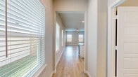 This well-designed two-story home offers four bedrooms and four bathrooms across two thoughtfully laid-out floors. The main level provides a welcoming foundation, featuring an open-concept kitchen and living area bathed in natural light from multiple windows fitted with clean white blinds. The kitchen is a standout, showcasing white shaker cabinetry with modern hardware, granite countertops, a light blue subway tile backsplash, and a full suite of stainless steel appliances. Light wood-tone flooring runs consistently throughout the main living areas, lending warmth and cohesion to the space. The living area connects seamlessly to an outdoor access point, with a glass door opening to the backyard. An attached garage with an automatic opener provides convenient enclosed parking. Upstairs, the more expansive floor hosts the majority of the bedrooms and bathrooms. The generously sized primary bedroom is complemented by a well-appointed en suite bathroom featuring dual vanities, a glass-enclosed shower, and a walk-in closet complete with built-in shelving and hanging rods. Additional bedrooms are bright and airy, each with ceiling fans and windows that invite natural light. The neutral color palette and clean finishes throughout create a fresh, modern ambiance ready to be personalized.