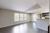This well-appointed two-bedroom, two-bathroom single-story home at 3415 Havenbrook Dr in Houston, Texas offers a thoughtfully designed layout with modern finishes throughout. The open living and dining area immediately impresses with its vaulted ceiling detail, neutral gray walls, and rich wood-style flooring that extends throughout the home. Multiple windows flood the space with natural light, offering views of the surrounding greenery and creating a bright, airy atmosphere. A pass-through counter connects the living area to the galley-style kitchen, which features dark espresso cabinetry, white countertops, black appliances including a range and refrigerator, and a convenient pass-through to the dedicated laundry area. The primary bedroom is generously sized and includes a ceiling fan, direct access to its own private bathroom, and a closet for ample storage. The second bedroom is equally comfortable, bathed in natural light from multiple windows. Both bathrooms are finished with dark wood cabinetry, white countertops, tiled tub-shower combinations, and wood-style flooring, maintaining a cohesive and modern aesthetic. A hallway connects the bedrooms and common areas, keeping the floor plan efficient and functional. This home offers a clean, contemporary feel throughout.