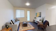 This well-appointed single-floor residence showcases a clean, contemporary design throughout. The open-concept kitchen serves as a central highlight, featuring textured flat-front cabinetry in a warm wood-grain finish, white quartz countertops, a subway tile backsplash, and a full suite of stainless steel appliances including a refrigerator, range, microwave, and dishwasher. A large central island with pendant lighting and bar seating provides an inviting space for dining and entertaining.

The living area offers a welcoming atmosphere with rich dark hardwood-style flooring, a full-light entry door, and a large window that fills the space with natural light. A hallway connects the main living spaces to the private rooms.

The primary bedroom is generously proportioned with plush carpeting and a neutral color palette. A secondary bedroom also features carpet flooring, a large window, and ample wall space. An additional flex room with carpet and a window serves well as a home office or den.

Two full bathrooms mirror each other in design, each featuring a tub-shower combination with brushed nickel fixtures, a modern floating vanity with wood-tone accents and a white countertop, dark hardwood-style flooring, and large mirrors.

Completing the unit is a dedicated in-unit laundry closet equipped with a full-size top-load washer and dryer.
